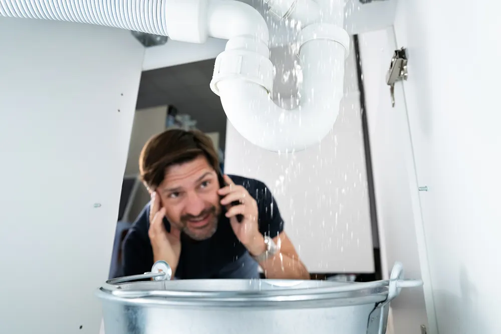 photo of a man looking at a leaking pipe